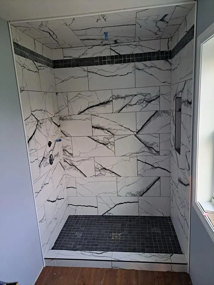 Black-vein porcelain shower with a dark mosaic floor