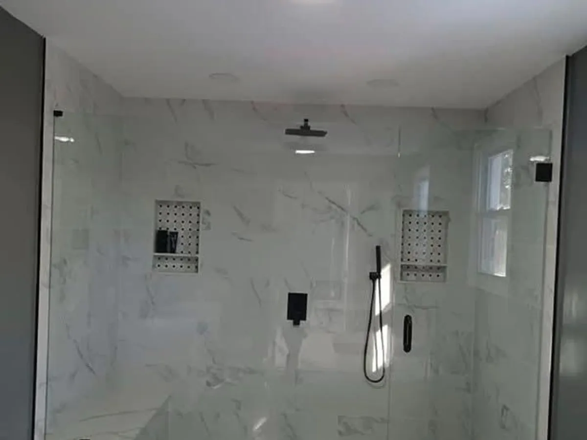 Walk-in shower with frameless glass, marble-look porcelain and matte black fixtures