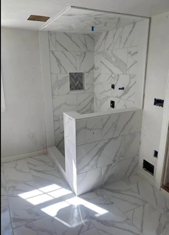 Marble-look shower with a half wall and niche